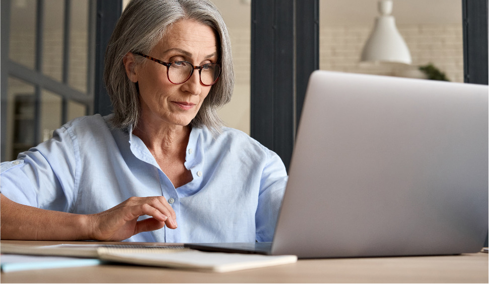 Grey haired woman sitting at computer