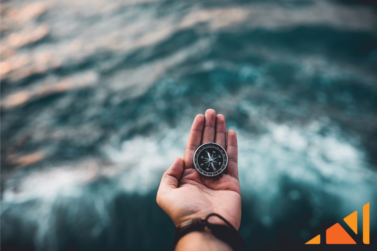 hand holding a compass over waves to illustrate how determining your purchase or investment mindset can guide your SDIRA decisions